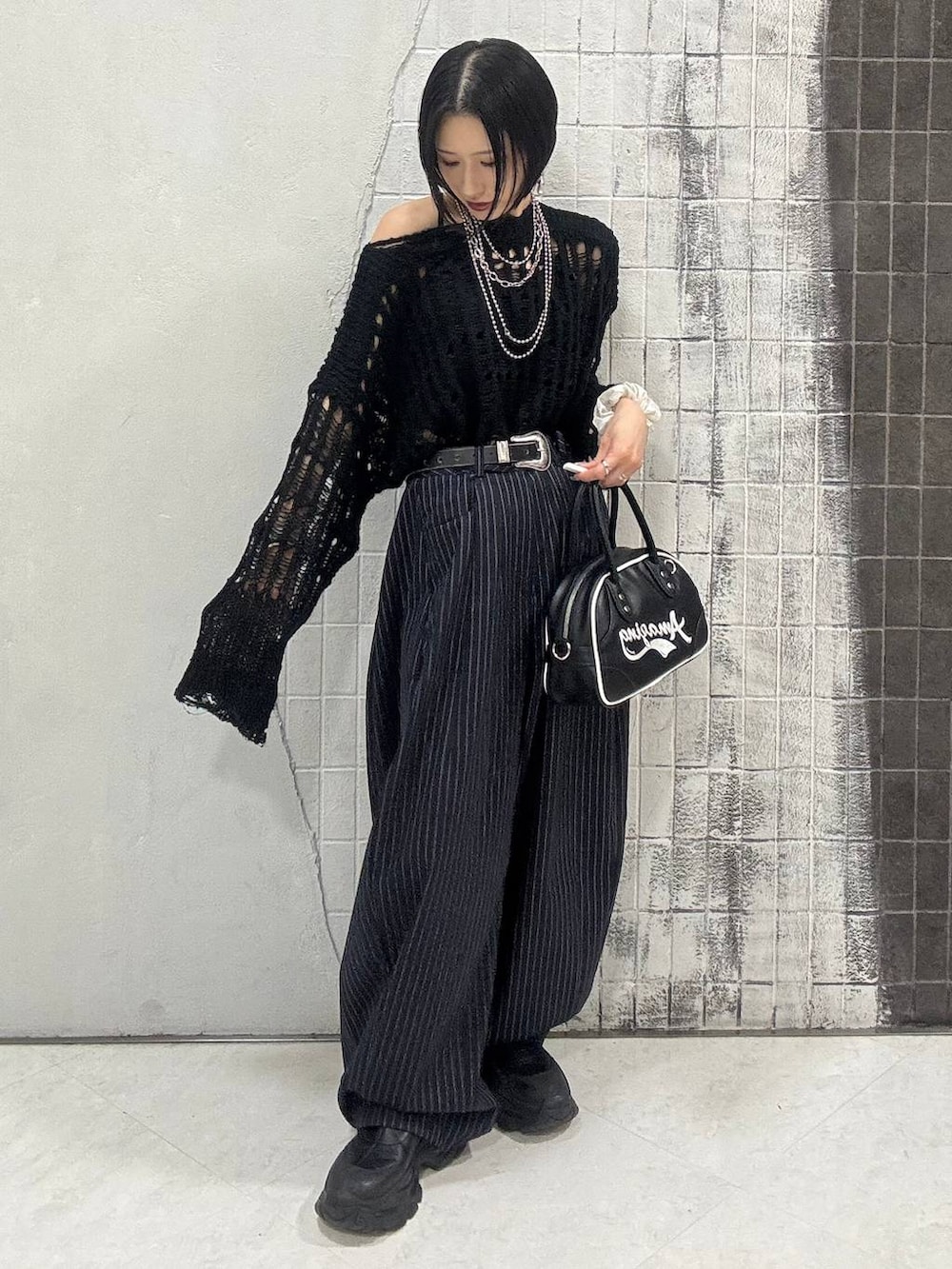 ブラック系のブーツ、ブルー系のスラックス、ブラック系のショルダーバッグを着用したレディースの秋コーディネートの8枚目の写真