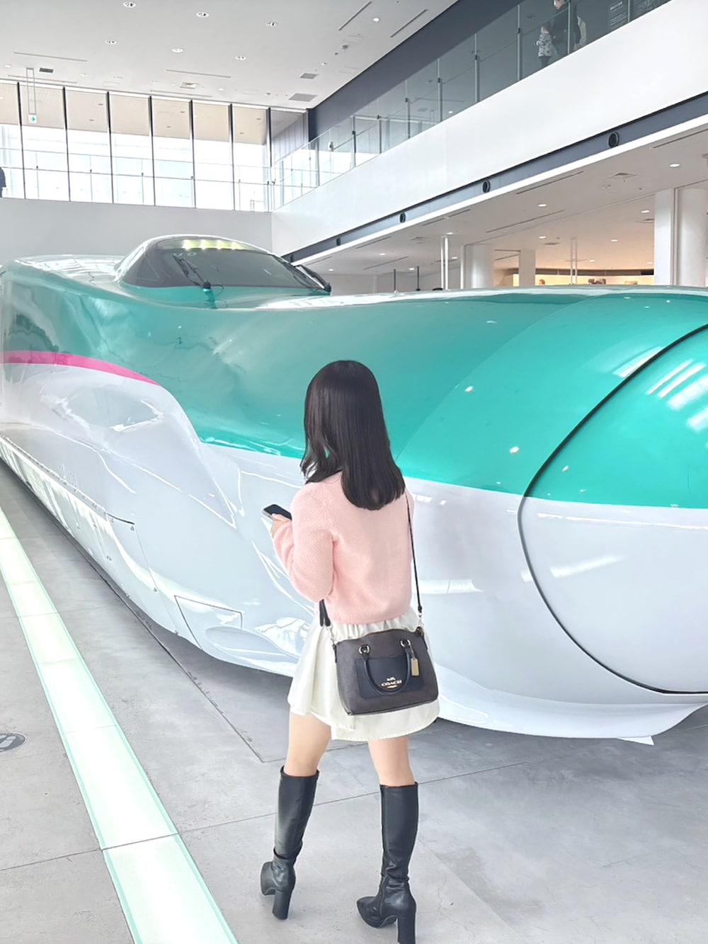 ピンク系のカーディガン/ボレロ、ホワイト系のシャツ/ブラウス、ブラック系のブーツを着用したレディースの春コーディネートの2枚目の写真