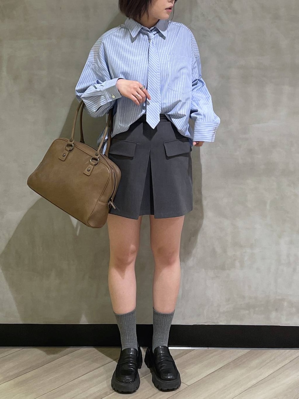 ベージュ系のボストンバッグ、ブラック系のローファー、グレー系のスカートを着用したレディースの冬コーディネートの5枚目の写真