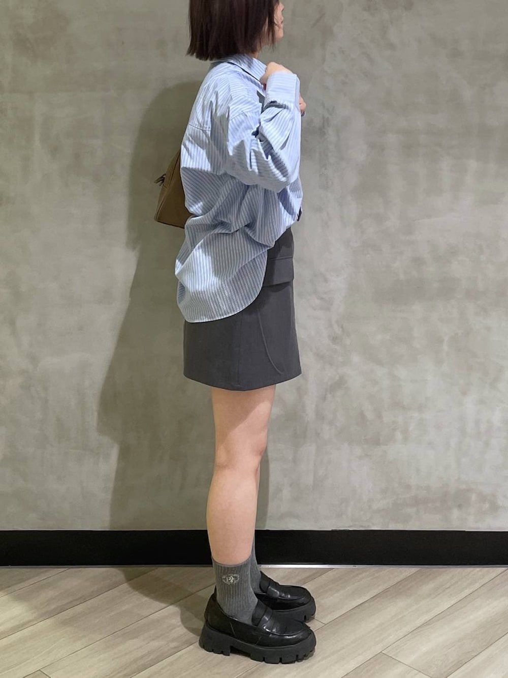 ベージュ系のボストンバッグ、ブラック系のローファー、グレー系のスカートを着用したレディースの冬コーディネートの4枚目の写真