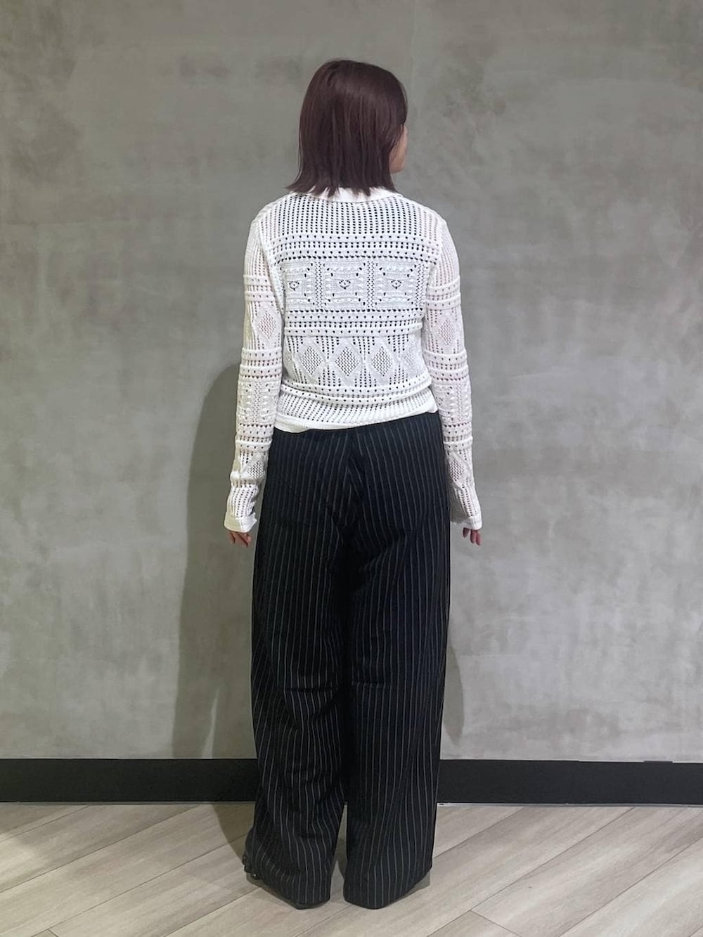 ブラック系のタンクトップ、ブラック系のスラックス、ホワイト系のカーディガン/ボレロを着用したレディースの春コーディネートの3枚目の写真