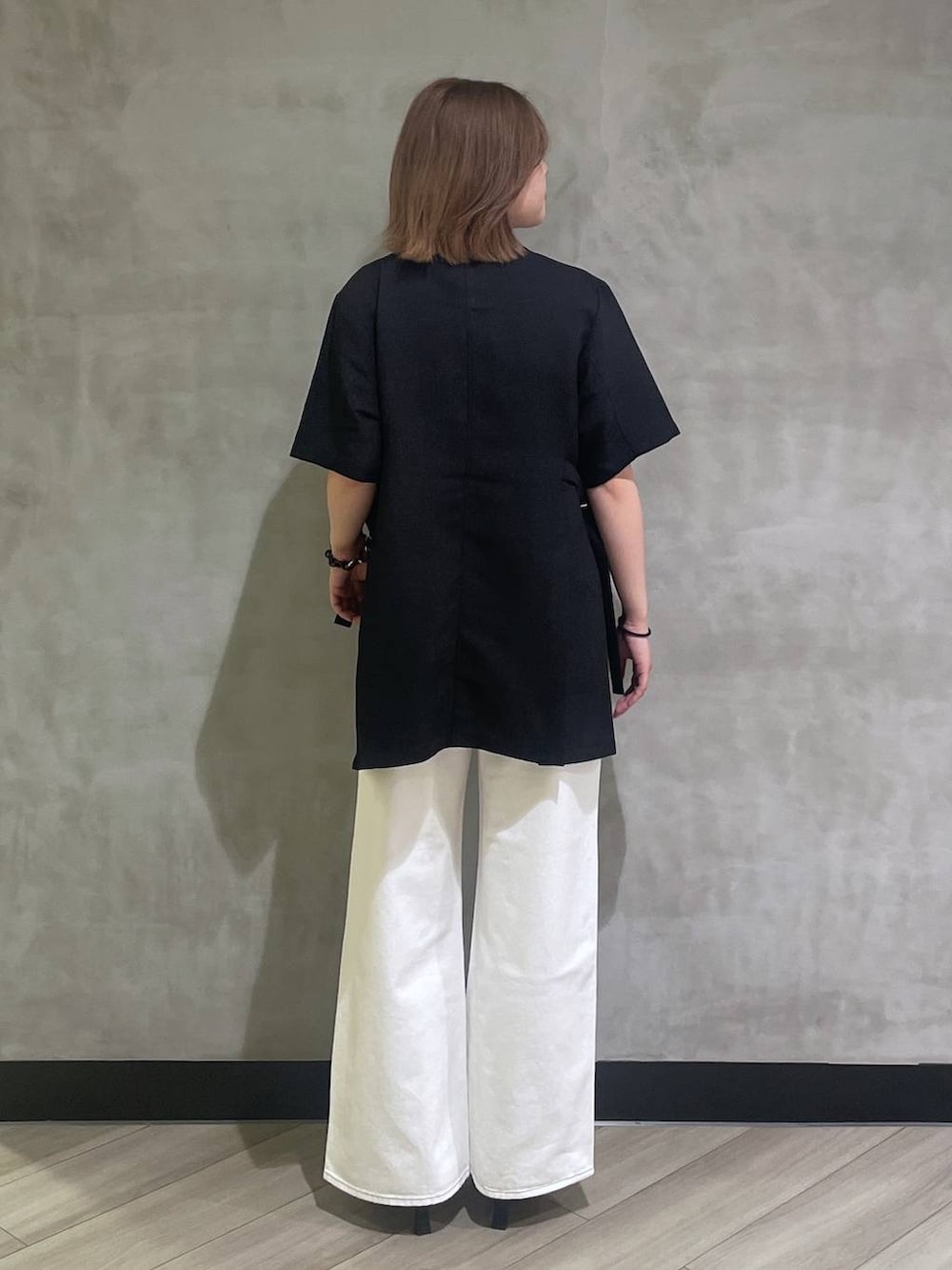 ホワイト系のデニムパンツ、ブラック系のサンダル、ブラック系のテーラードジャケットを着用したレディースの春コーディネートの3枚目の写真