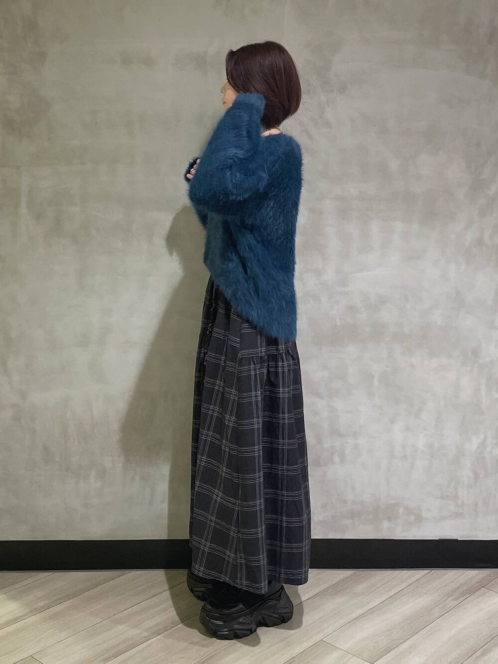 ホワイト系のブーツ、ブルー系のニット/セーター、ブラック系のスカートを着用したレディースの秋コーディネートの2枚目の写真