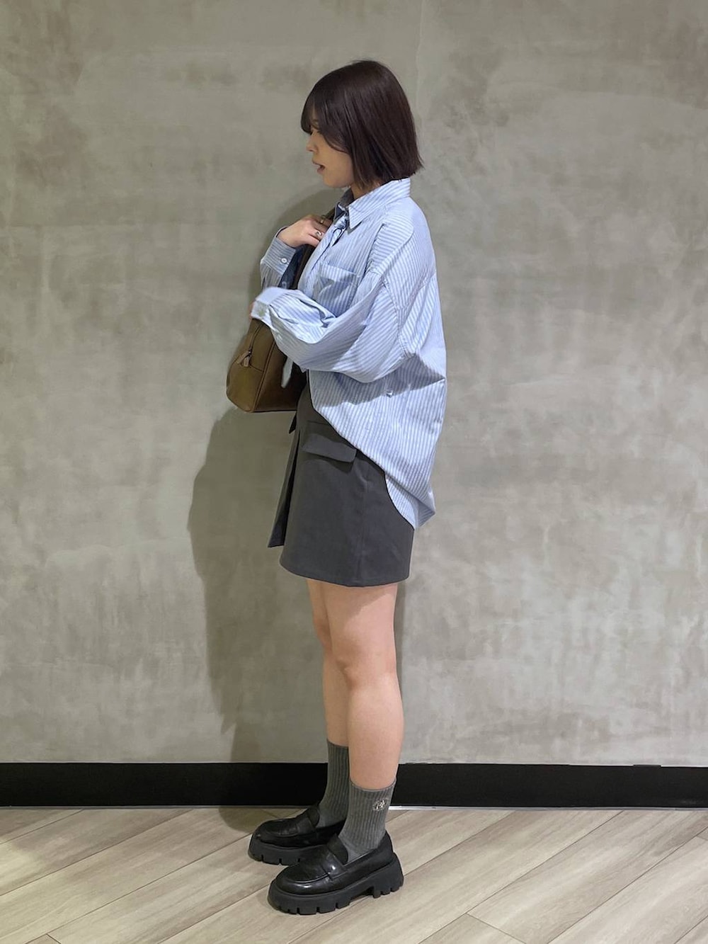 ベージュ系のボストンバッグ、ブラック系のローファー、グレー系のスカートを着用したレディースの冬コーディネートの2枚目の写真