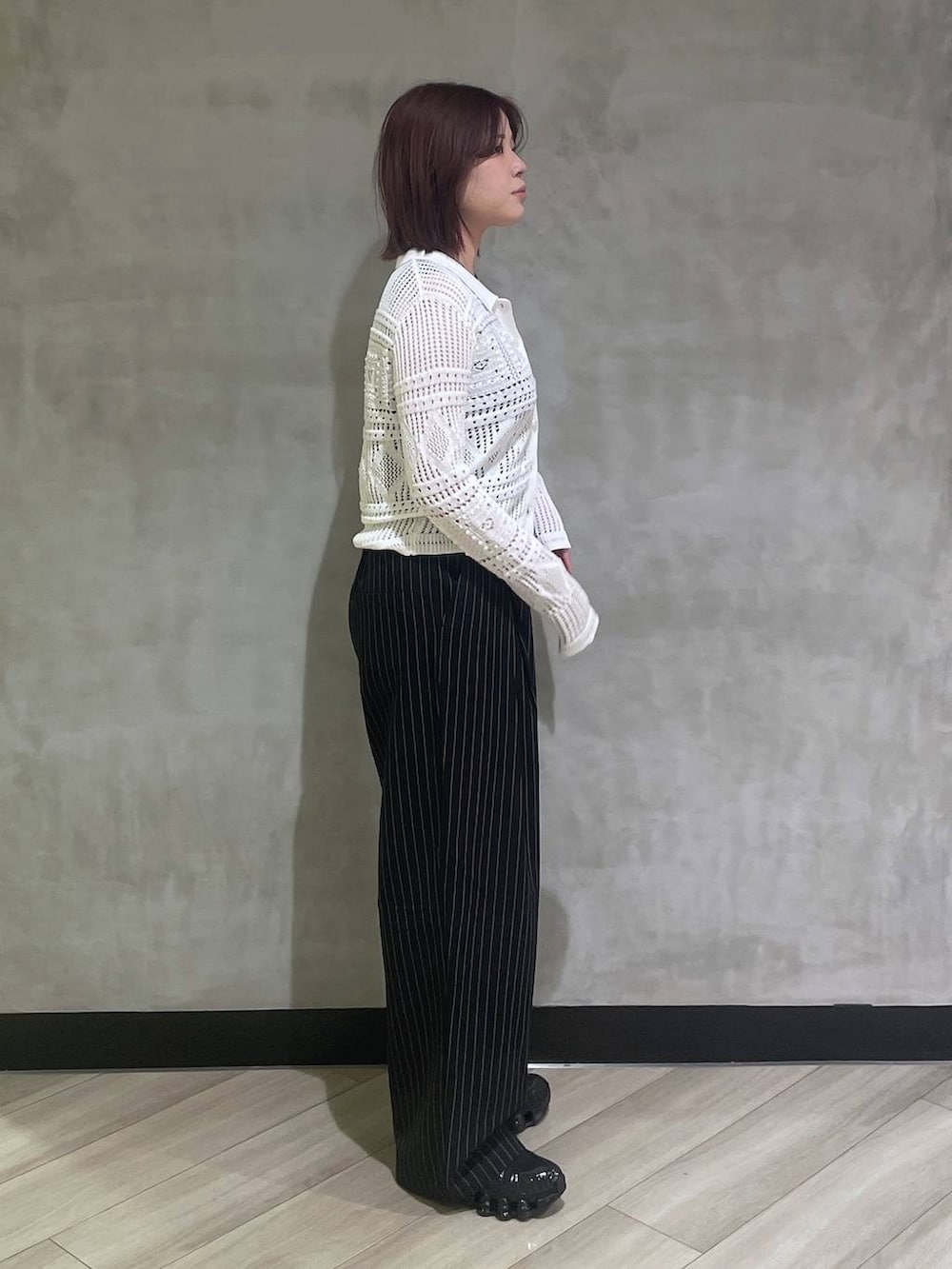 ブラック系のタンクトップ、ブラック系のスラックス、ホワイト系のカーディガン/ボレロを着用したレディースの春コーディネートの4枚目の写真