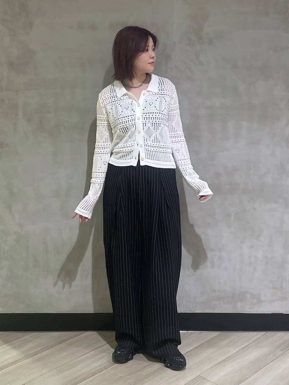 ブラック系のタンクトップ、ブラック系のスラックス、ホワイト系のカーディガン/ボレロを着用したレディースの春コーディネートの5枚目の写真