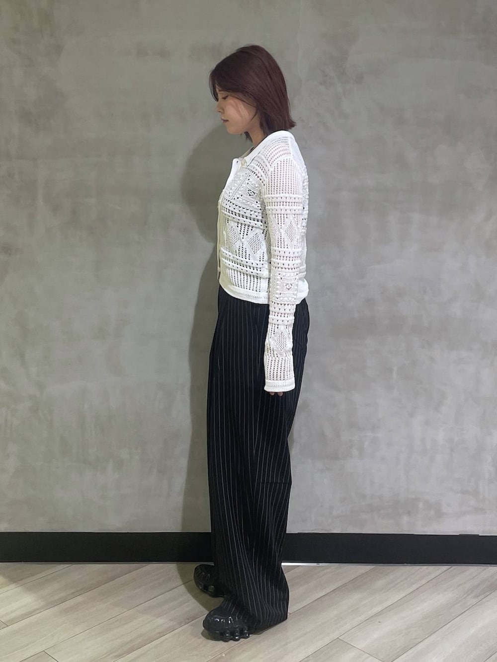 ブラック系のタンクトップ、ブラック系のスラックス、ホワイト系のカーディガン/ボレロを着用したレディースの春コーディネートの2枚目の写真