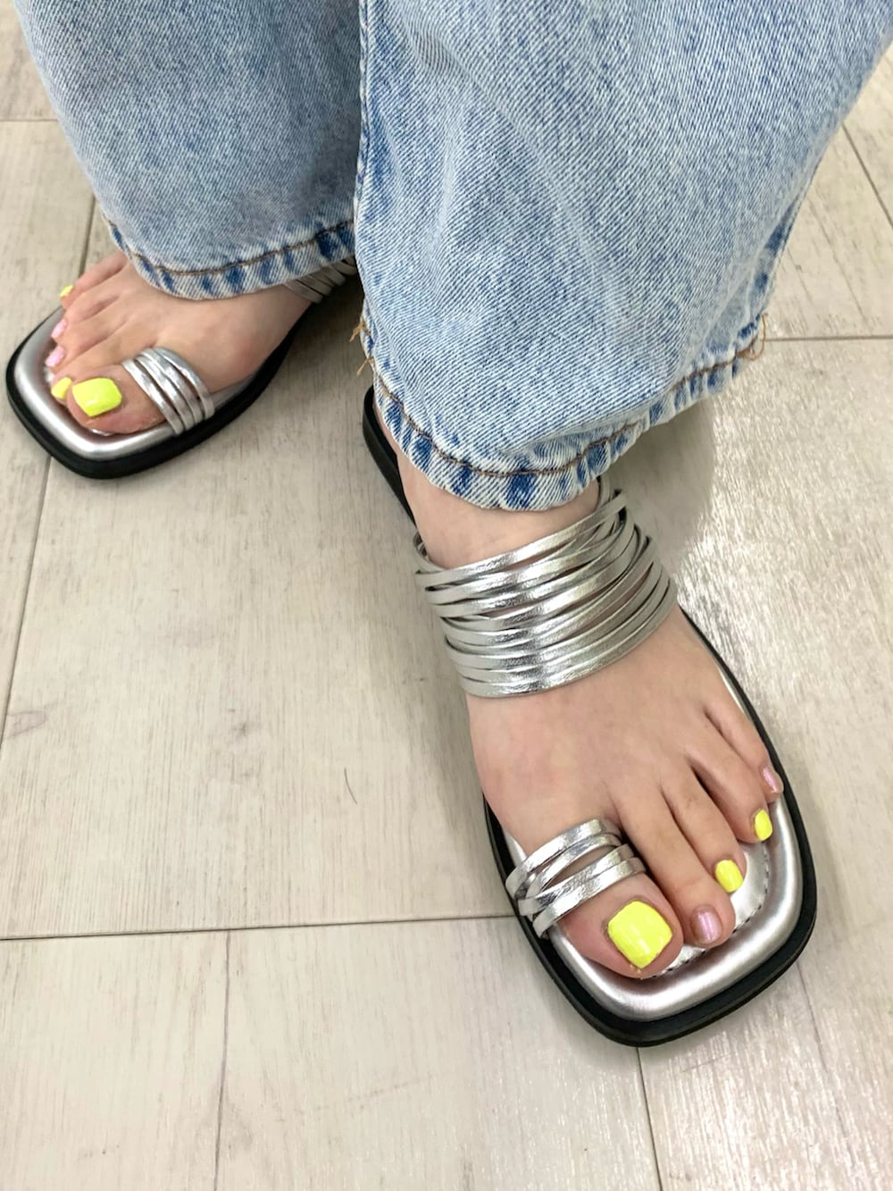 シルバー系のサンダル、ブルー系のデニムパンツ、ベージュ系のトップスを着用したレディースの夏コーディネートの2枚目の写真