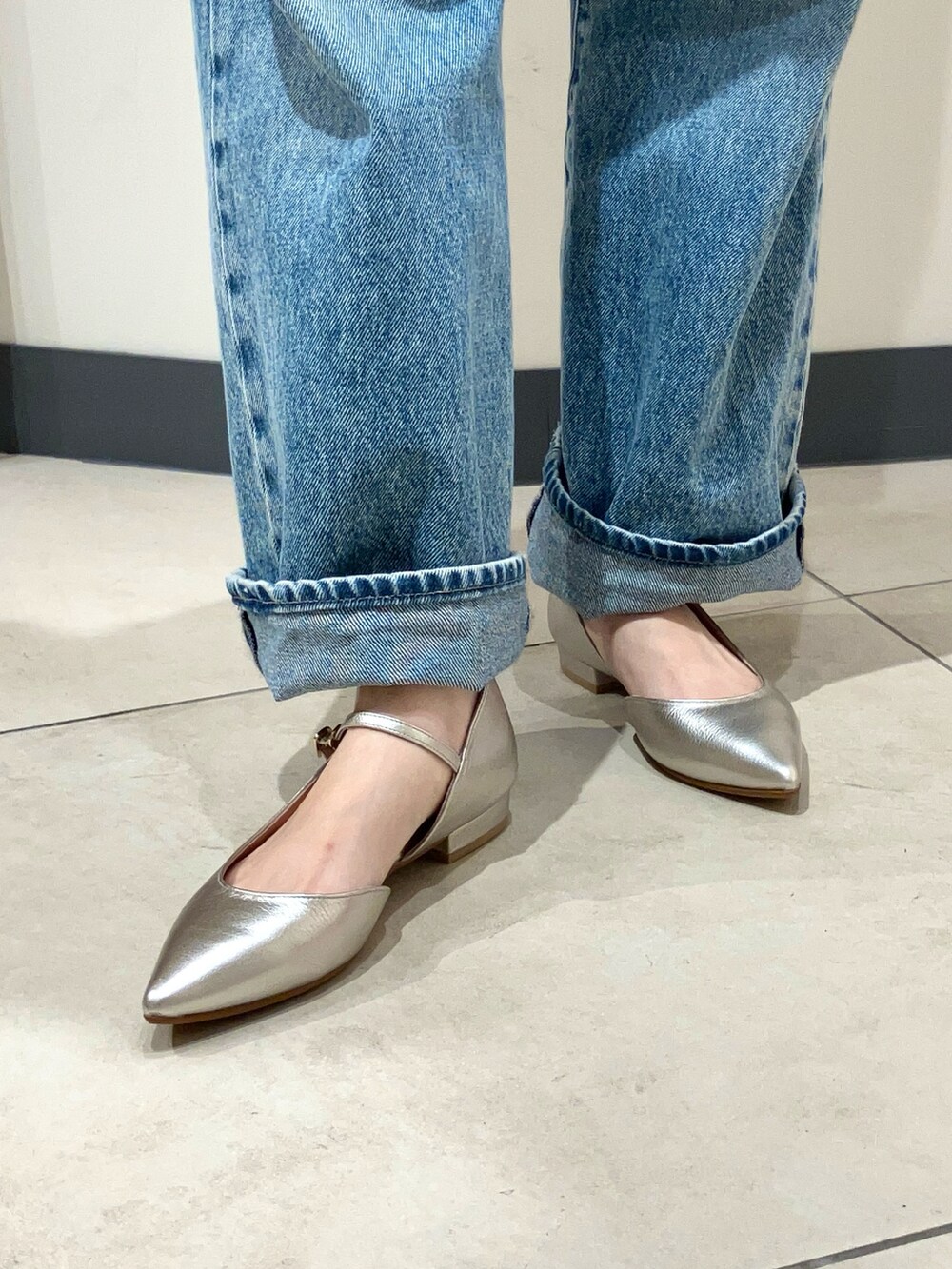 シルバー系のパンプス、ブルー系のデニムパンツ、ブラウン系のニット/セーターを着用したレディースの秋コーディネートの2枚目の写真