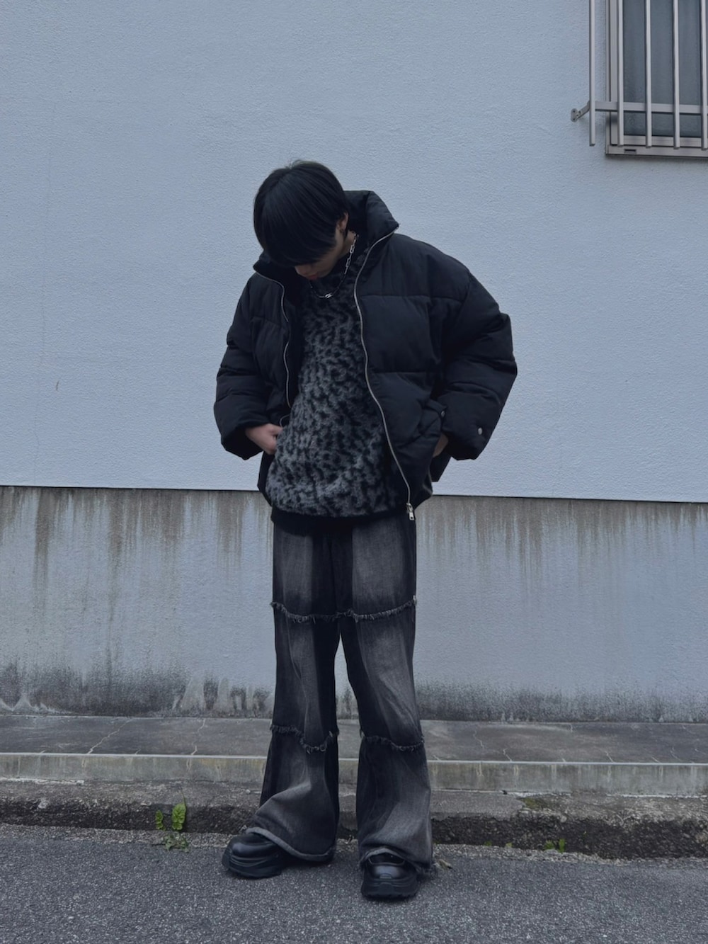 ブラック系のダウンジャケット/コート、ブラック系のデニムパンツ、ブラック系のニット/セーターを着用したメンズの春コーディネートの2枚目の写真