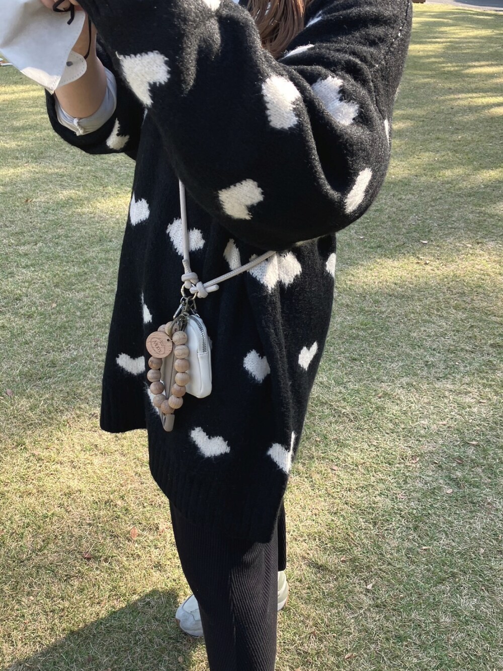 ブラック系のニット/セーター、ホワイト系のスニーカー、ブラック系のスカートを着用したレディースの秋コーディネートの2枚目の写真