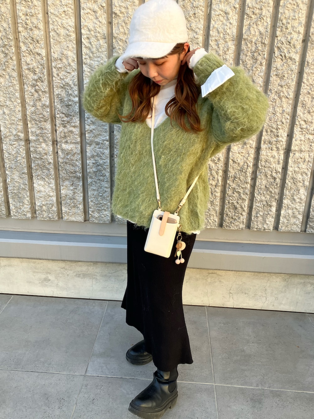 グリーン系のニット/セーター、ホワイト系のその他アウター、ブラック系のスカートを着用したレディースの冬コーディネートの2枚目の写真