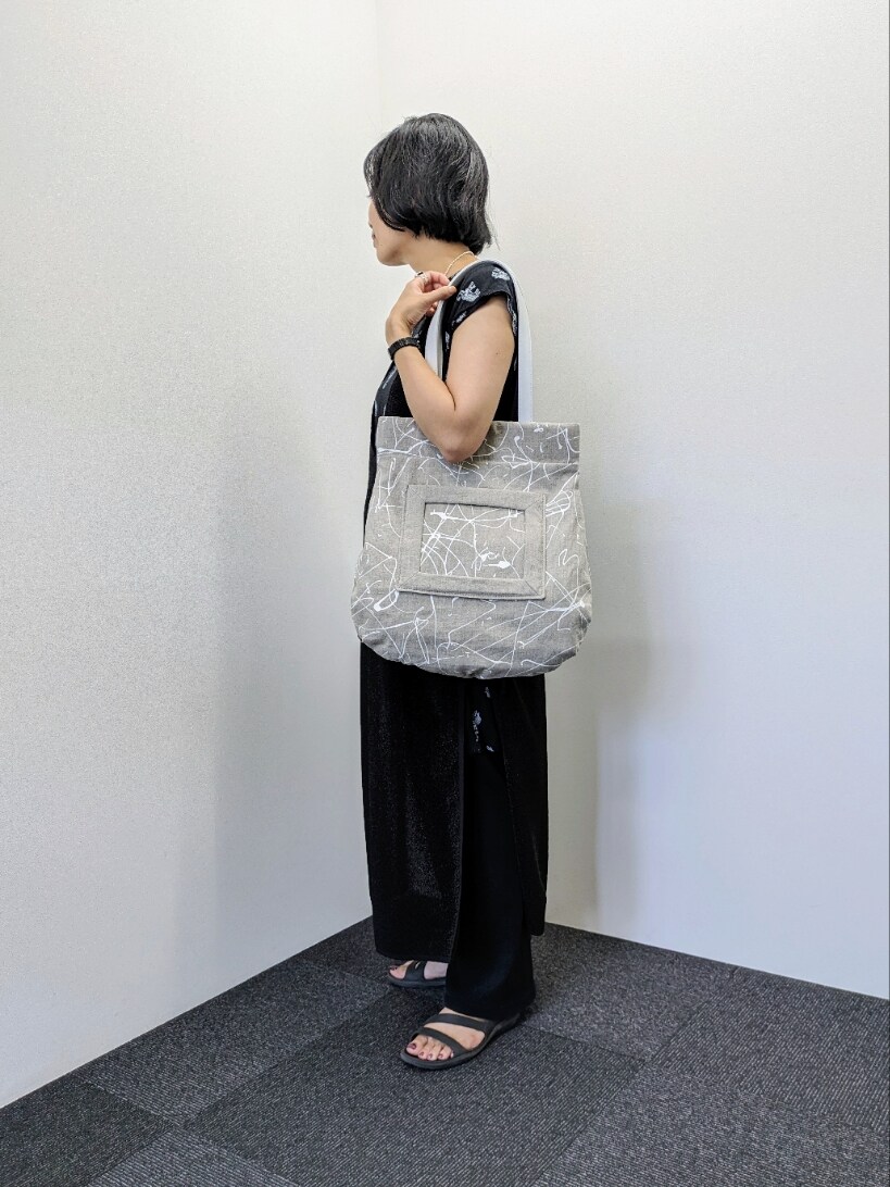 ベージュ系のトートバッグを着用したレディースの夏コーディネートの2枚目の写真