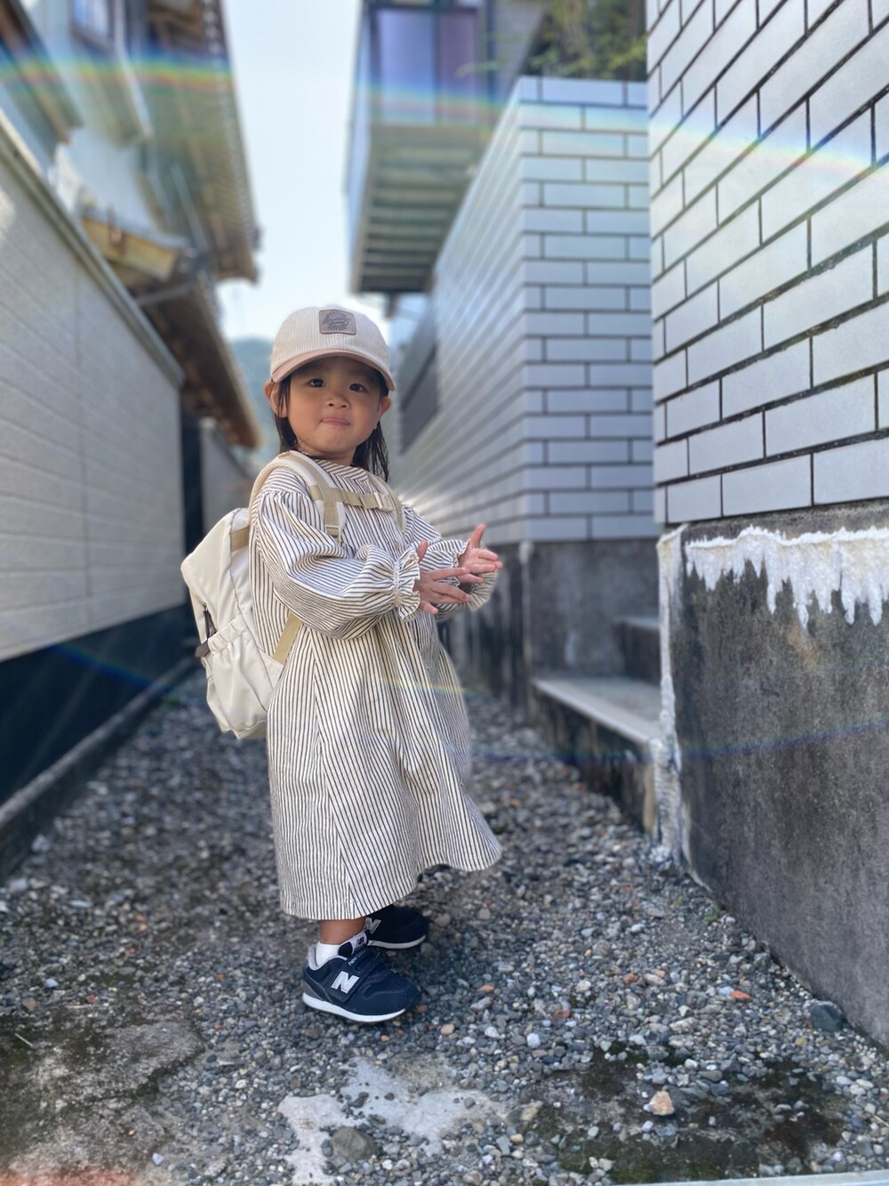 ブルー系のスニーカー、ホワイト系のシャツワンピース、ベージュ系のキャップを着用したキッズの秋コーディネートの2枚目の写真
