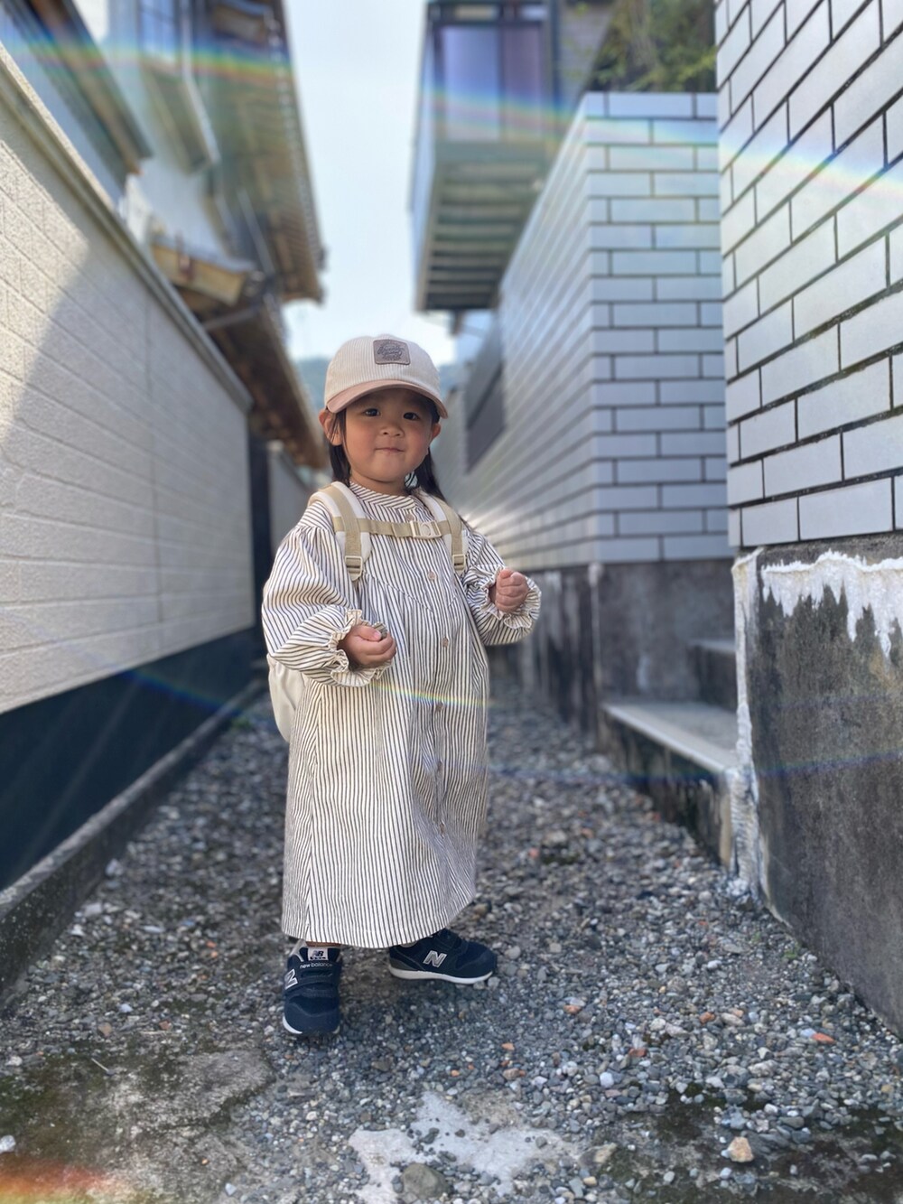 ブルー系のスニーカー、ホワイト系のシャツワンピース、ベージュ系のキャップを着用したキッズの秋コーディネートの3枚目の写真