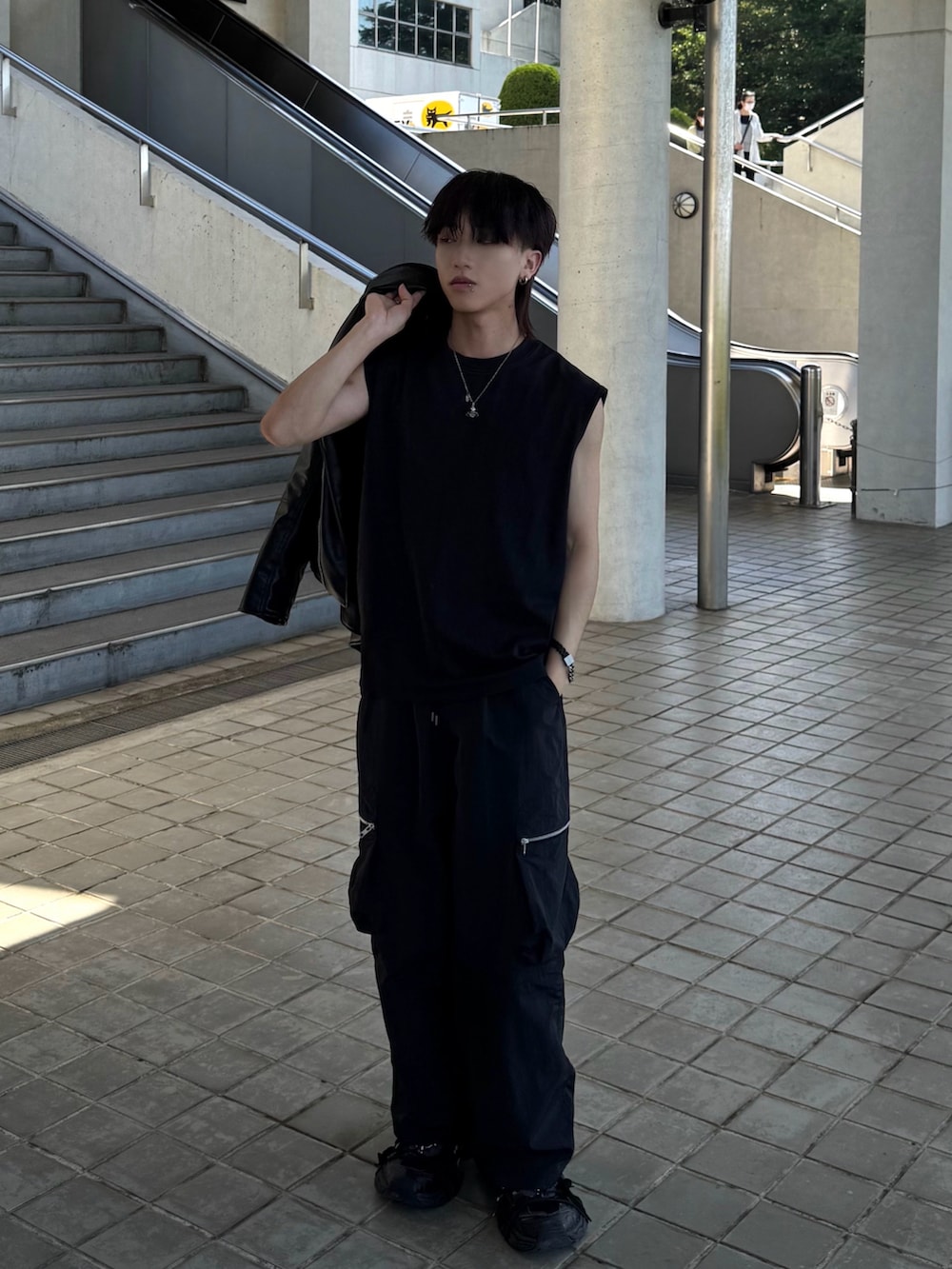 ブラック系のタンクトップ、ブラック系のカーゴパンツ、ブラック系のスニーカーを着用したメンズの春コーディネートの3枚目の写真