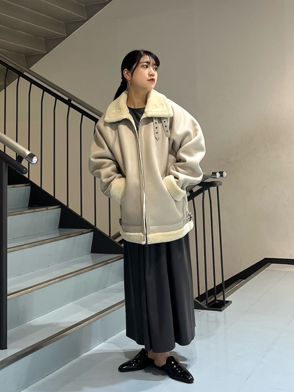 グレー系のムートンコート、グレー系のワンピース、シルバー系のイヤリングを着用したレディースの冬コーディネートの2枚目の写真