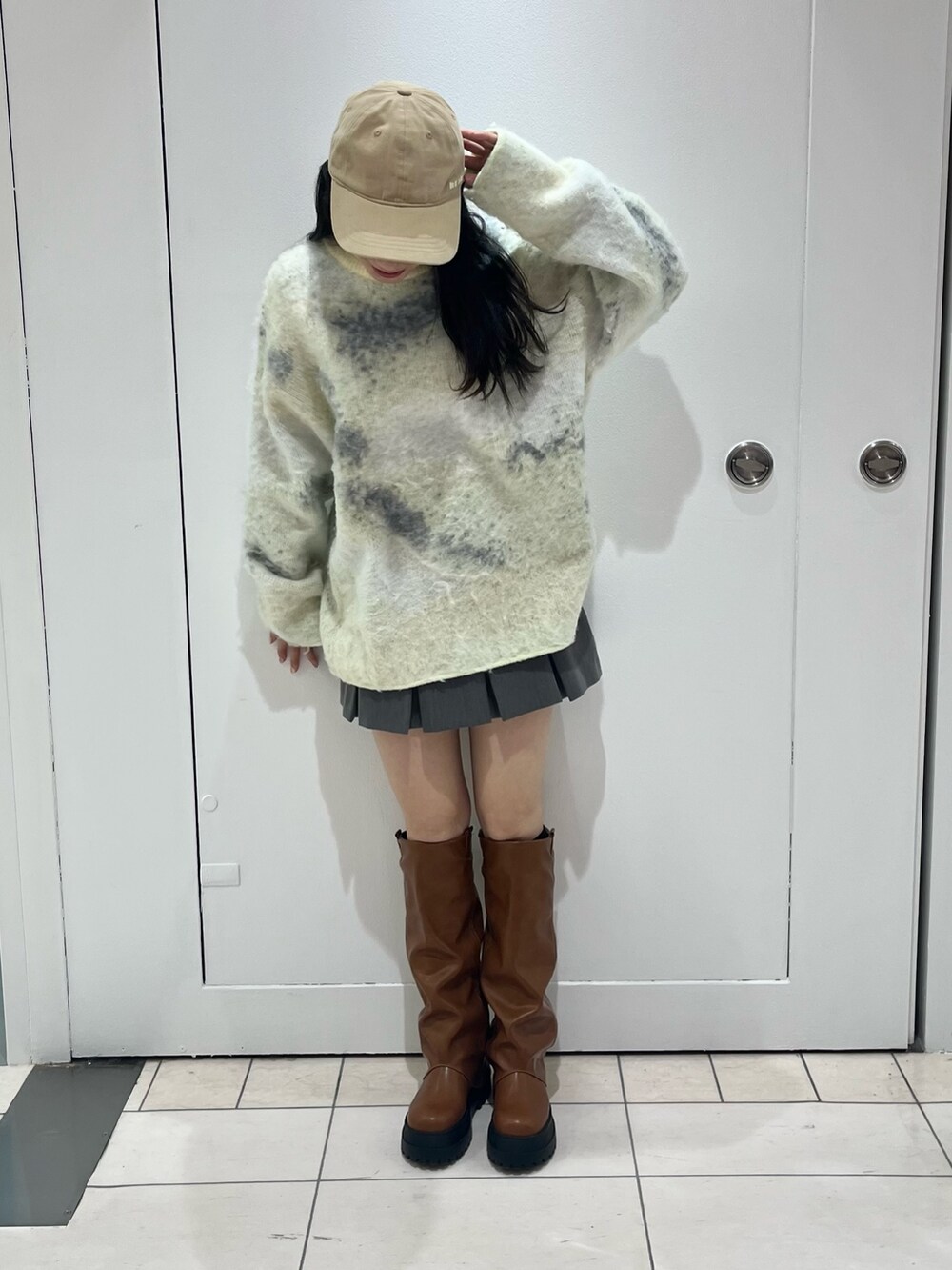 グリーン系のニット/セーター、ブラウン系のブーツ、ベージュ系のキャップを着用したレディースの冬コーディネートの2枚目の写真