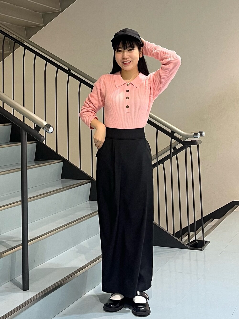 ブラック系のワンピース、ピンク系のニット/セーター、ブラック系のキャップを着用したレディースの冬コーディネートの3枚目の写真