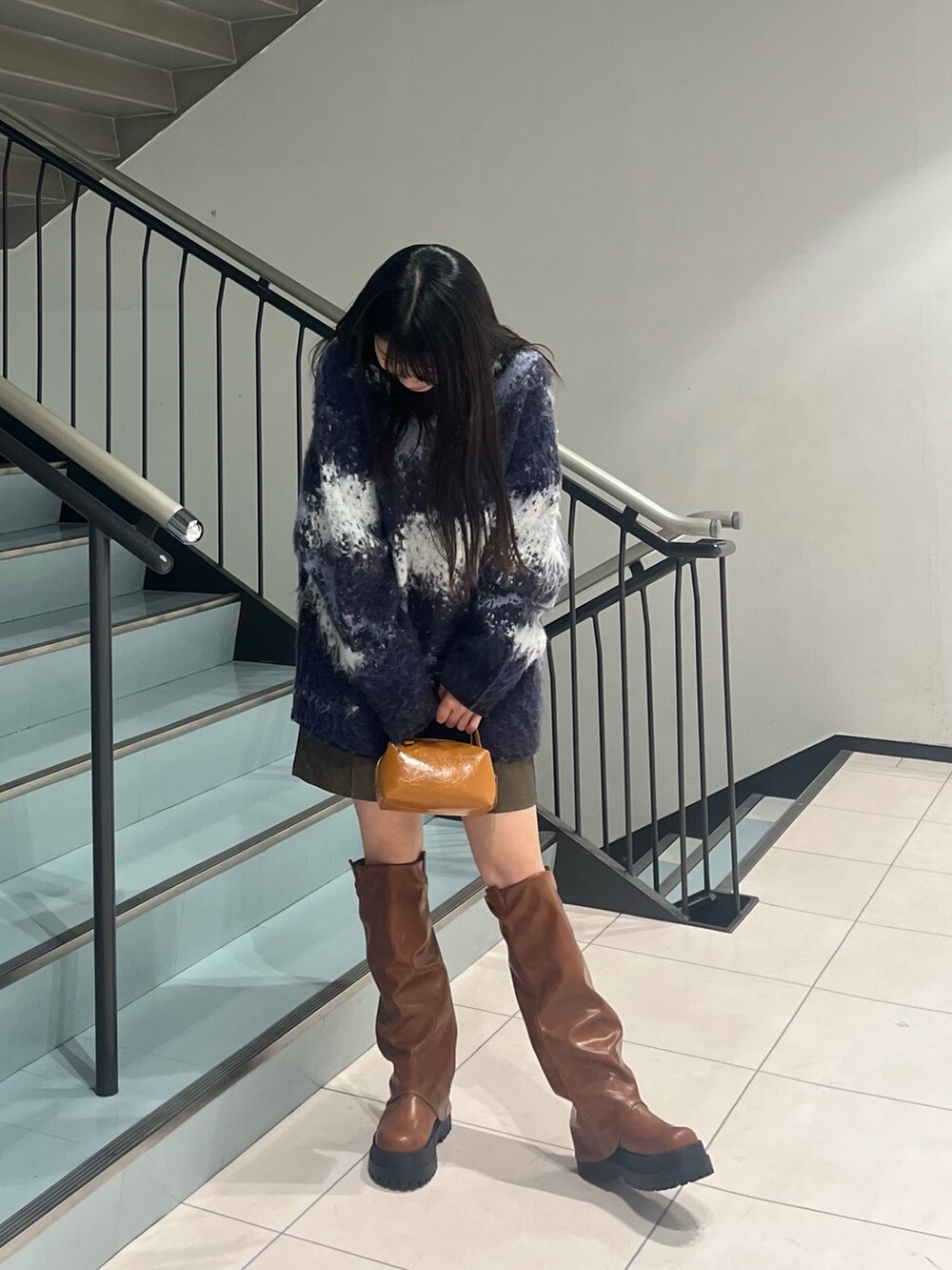 ブルー系のニット/セーター、ブラウン系のその他パンツ、イエロー系のハンドバッグを着用したレディースの冬コーディネートの2枚目の写真