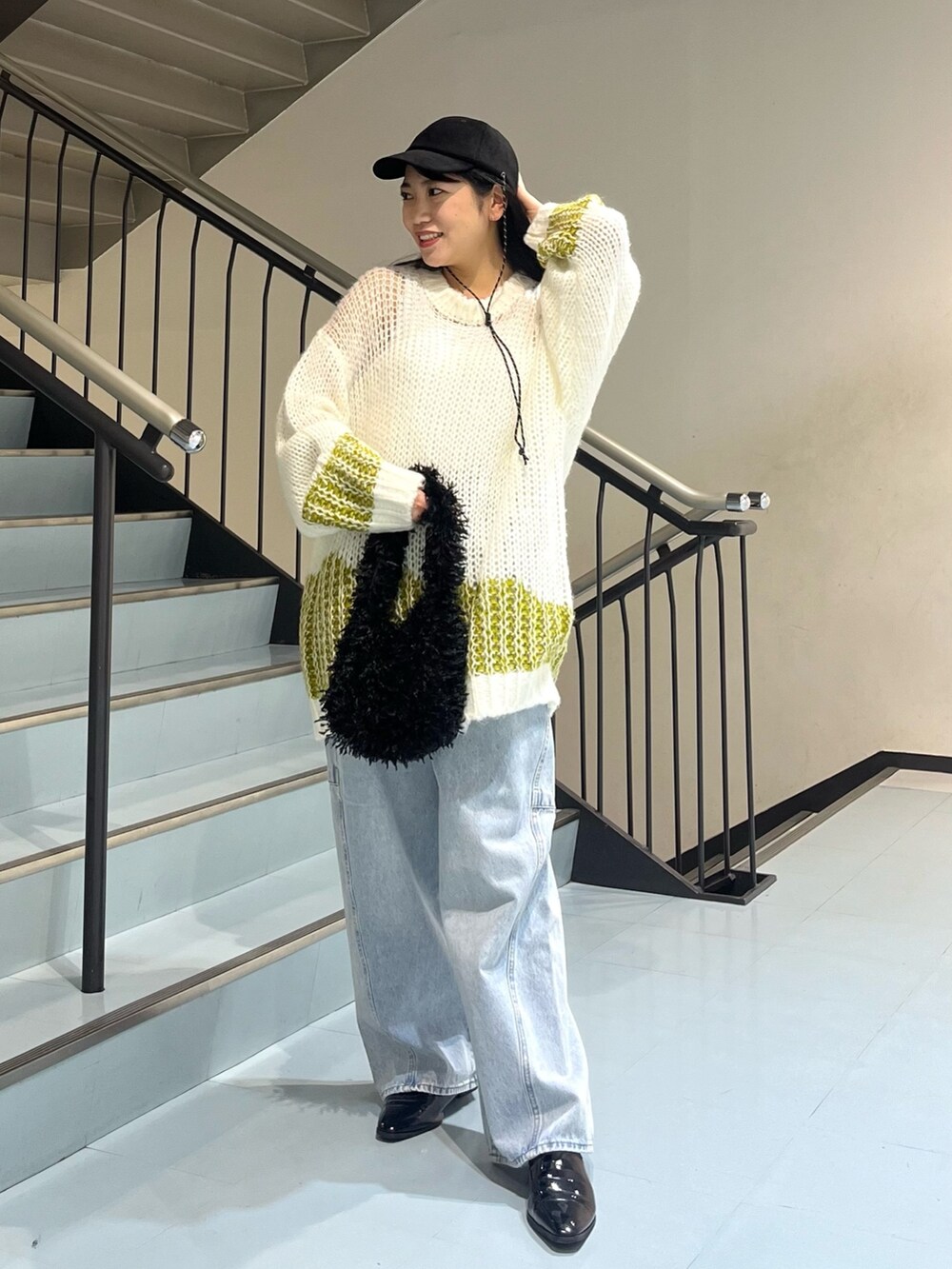 ブルー系のデニムパンツ、ホワイト系のニット/セーター、ブラック系のショルダーバッグを着用したレディースの冬コーディネートの2枚目の写真