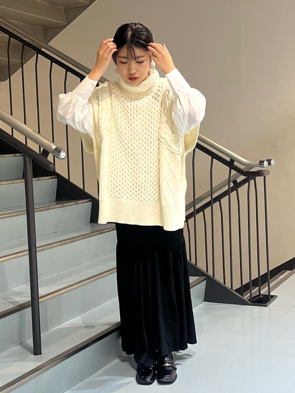 ホワイト系のニット/セーター、ホワイト系のシャツ/ブラウス、ブラック系のスカートを着用したレディースの秋コーディネートの2枚目の写真