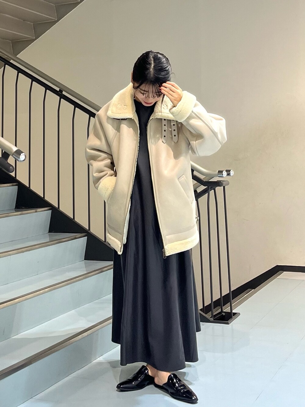 グレー系のムートンコート、グレー系のワンピース、シルバー系のイヤリングを着用したレディースの冬コーディネートの3枚目の写真