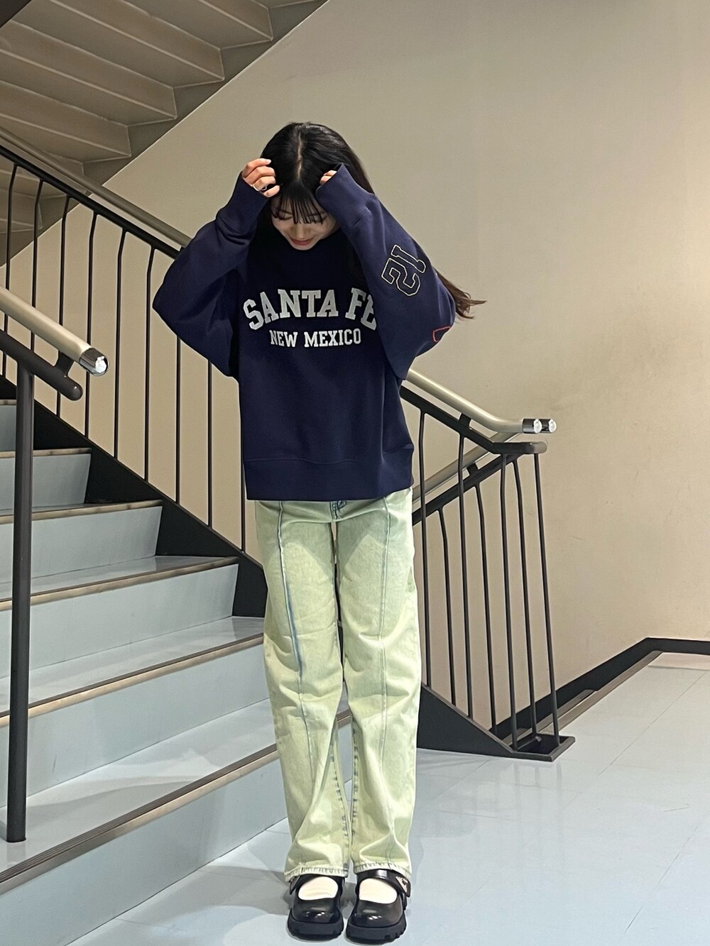 グリーン系のデニムパンツ、ブルー系のスウェットを着用したレディースの秋コーディネートの2枚目の写真