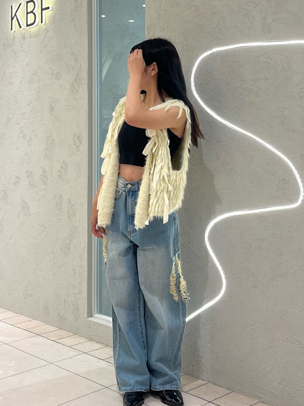 ブルー系のデニムパンツ、ホワイト系のベストを着用したレディースの秋コーディネートの2枚目の写真