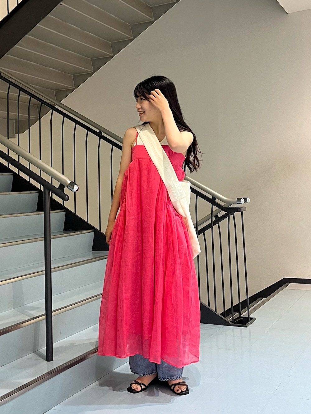 ピンク系のワンピース、ブルー系のデニムパンツ、ホワイト系のショルダーバッグを着用したレディースの夏コーディネートの2枚目の写真