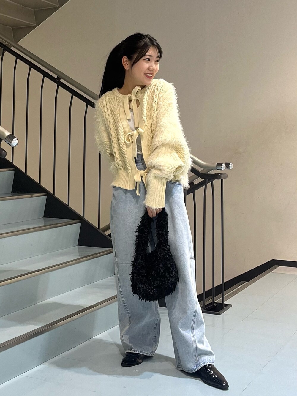 ホワイト系のニット/セーター、ブルー系のデニムパンツ、ブラック系のショルダーバッグを着用したレディースの冬コーディネートの3枚目の写真