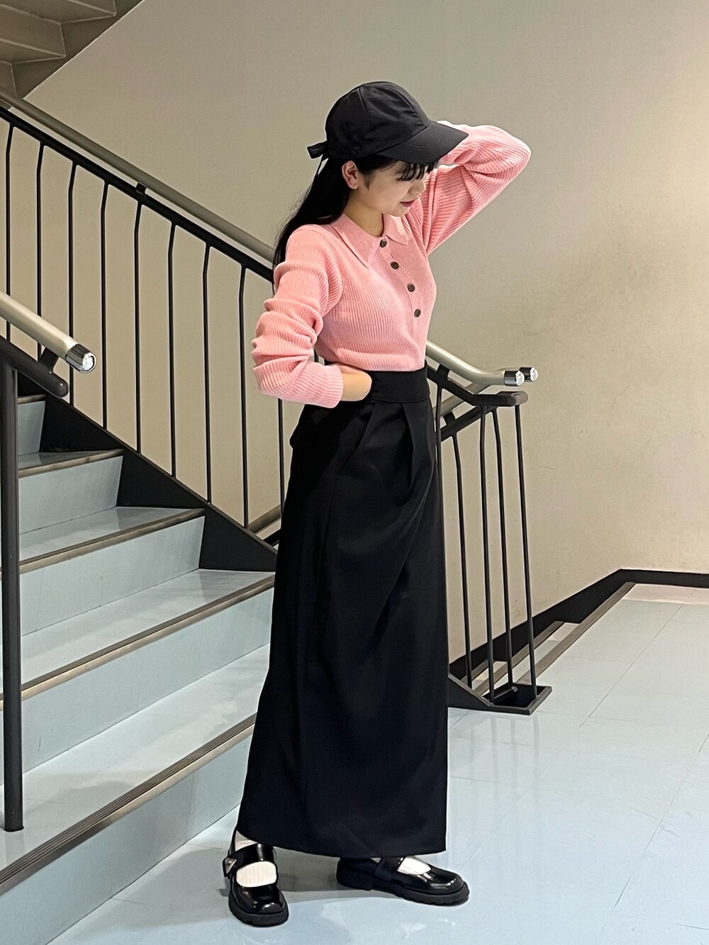 ブラック系のワンピース、ピンク系のニット/セーター、ブラック系のキャップを着用したレディースの冬コーディネートの2枚目の写真