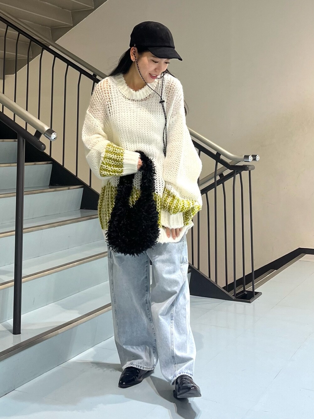 ブルー系のデニムパンツ、ホワイト系のニット/セーター、ブラック系のショルダーバッグを着用したレディースの冬コーディネートの3枚目の写真