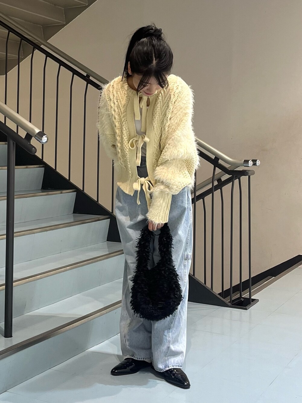 ホワイト系のニット/セーター、ブルー系のデニムパンツ、ブラック系のショルダーバッグを着用したレディースの冬コーディネートの2枚目の写真