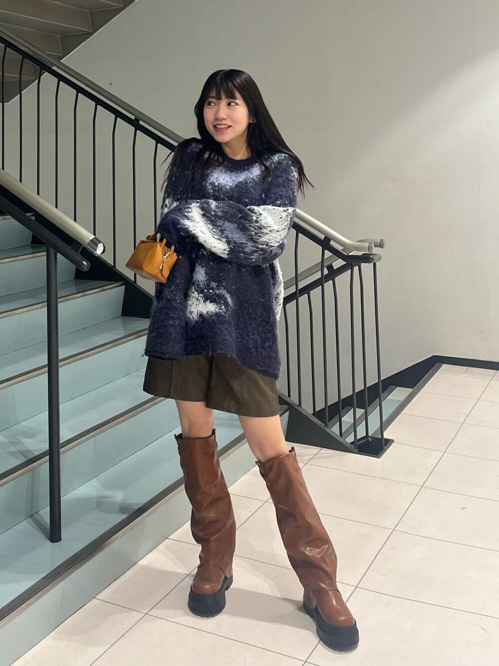 ブルー系のニット/セーター、ブラウン系のその他パンツ、イエロー系のハンドバッグを着用したレディースの冬コーディネートの3枚目の写真