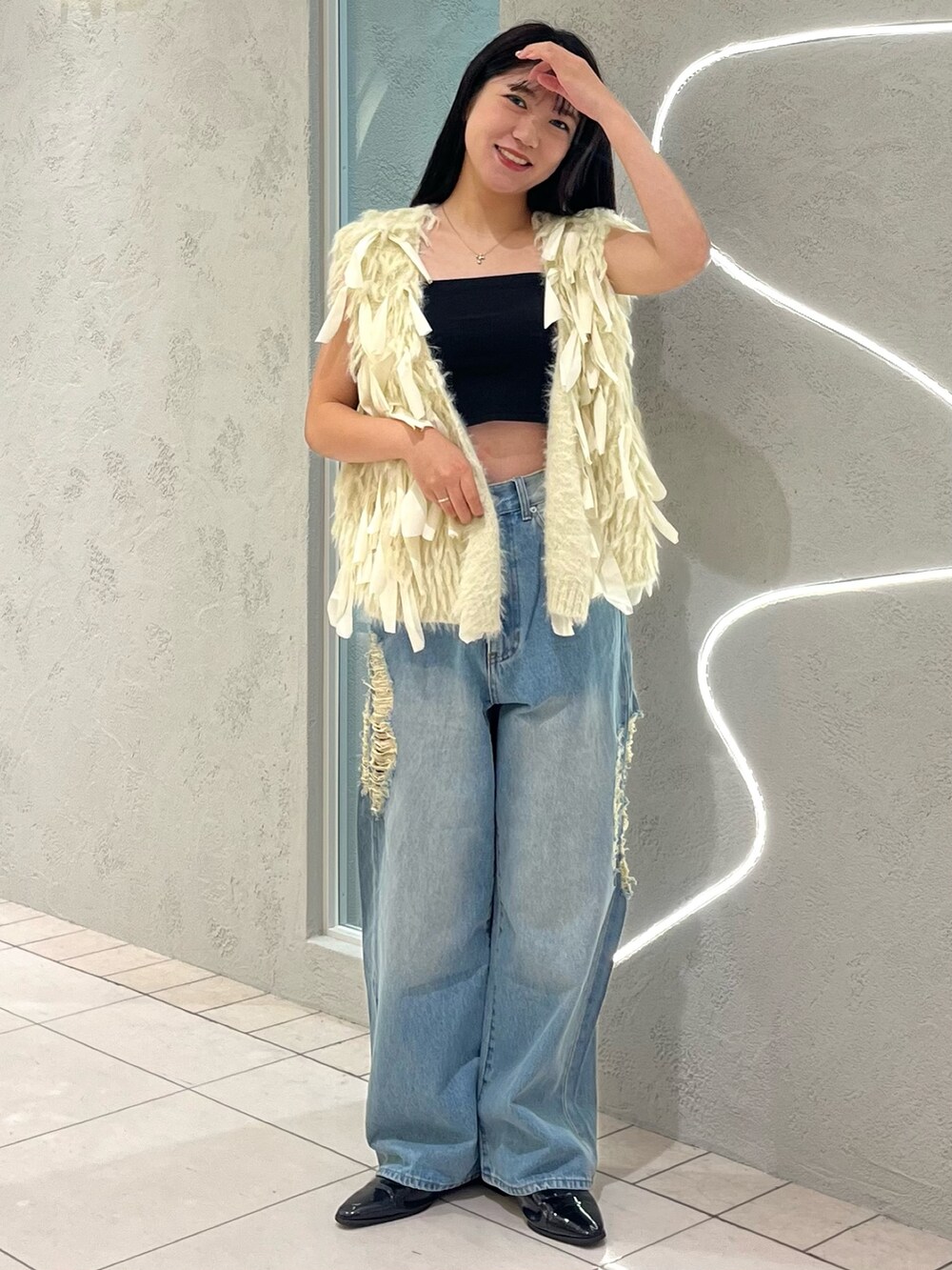 ブルー系のデニムパンツ、ホワイト系のベストを着用したレディースの秋コーディネートの3枚目の写真