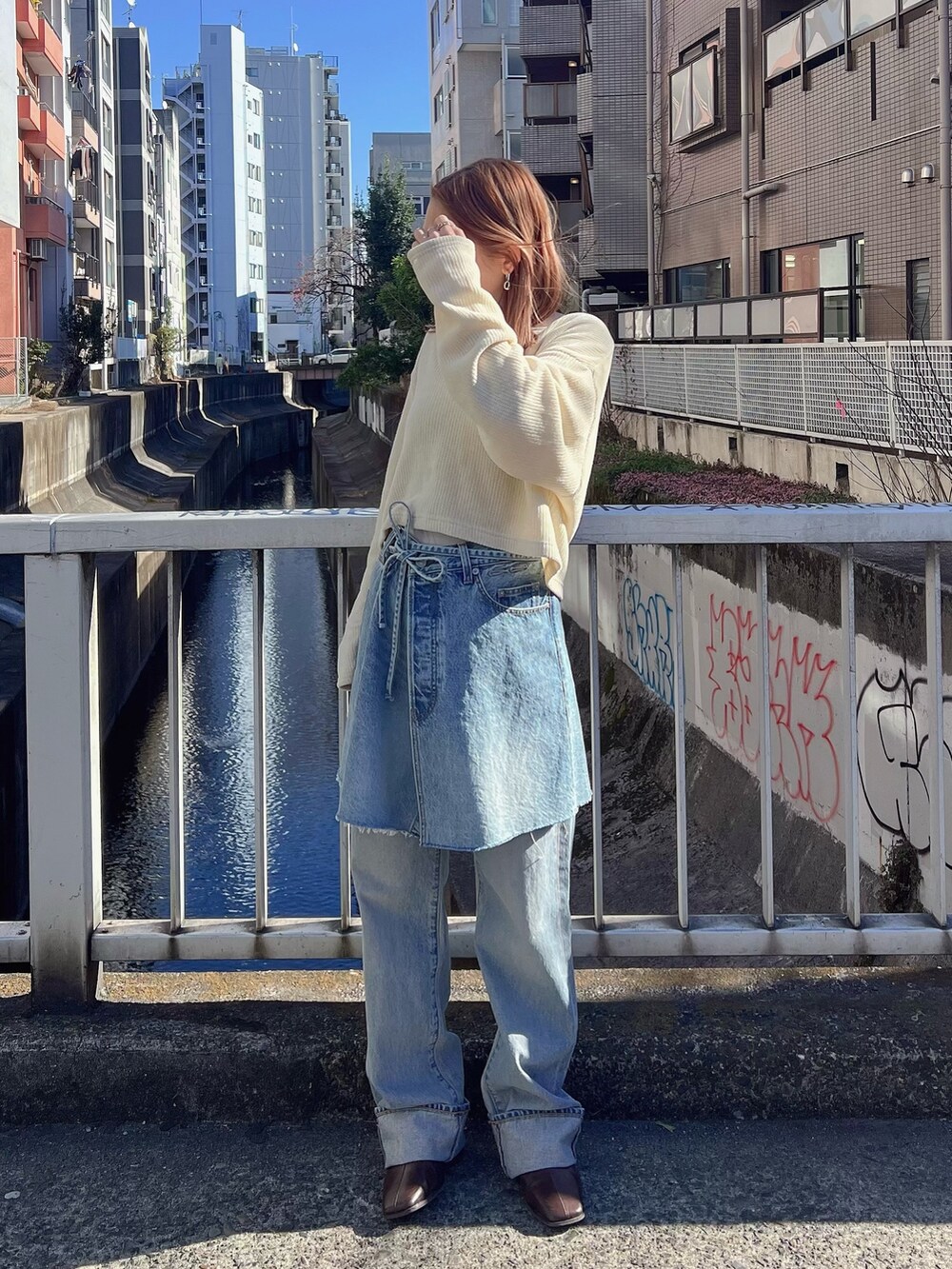 イエロー系のTシャツ/カットソー、ブルー系のスカート、ブルー系のデニムパンツを着用したレディースの冬コーディネートの2枚目の写真