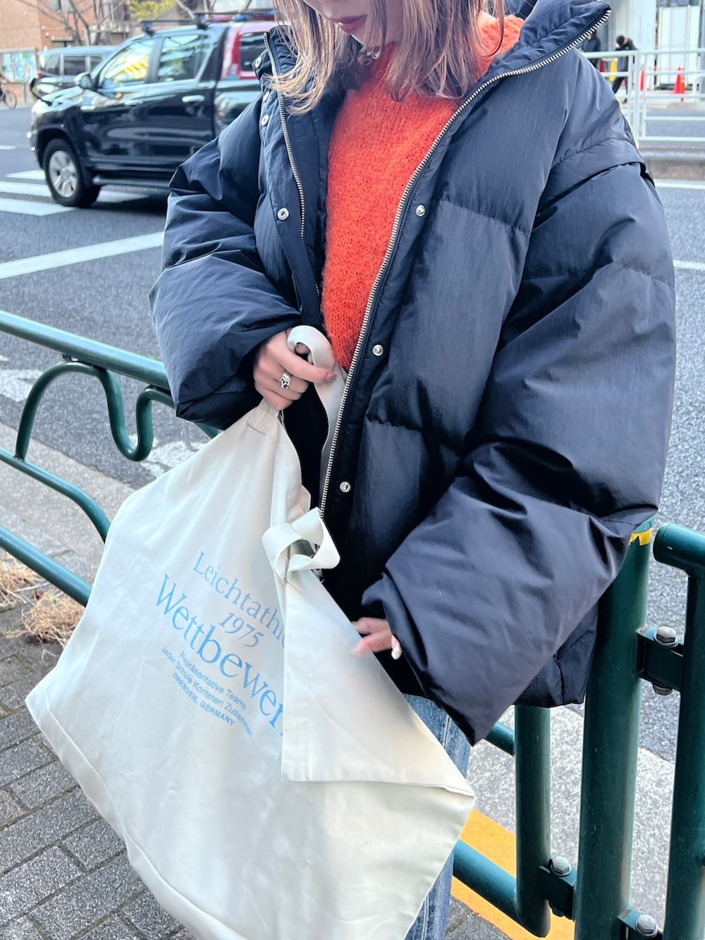 ブラック系のダウンジャケット/コート、ブルー系のデニムパンツ、オレンジ系のニット/セーターを着用したレディースの冬コーディネートの3枚目の写真