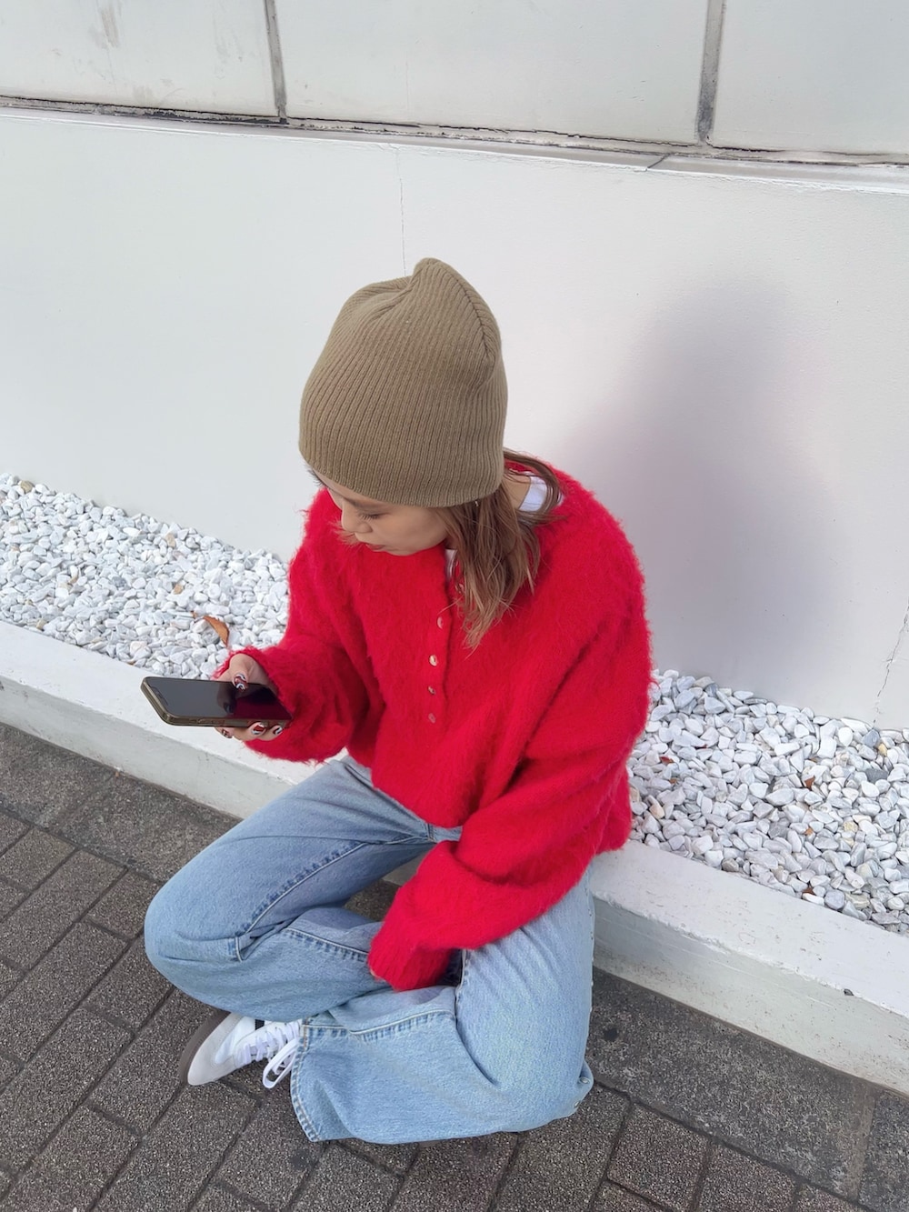 ブラウン系のブルゾン、レッド系のニット/セーター、ブルー系のデニムパンツを着用したレディースの冬コーディネートの2枚目の写真