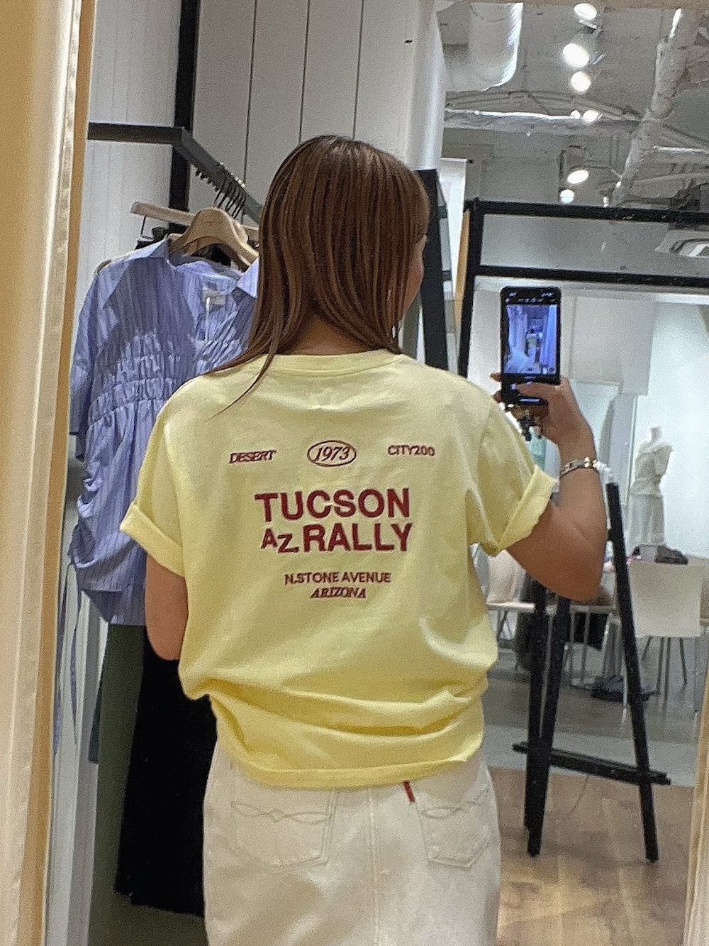 グリーン系のブルゾン、イエロー系のTシャツ/カットソー、ホワイト系のスカートを着用したレディースの春コーディネートの3枚目の写真