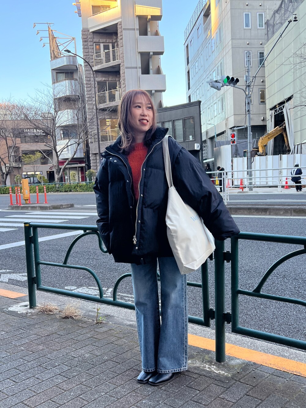 ブラック系のダウンジャケット/コート、ブルー系のデニムパンツ、オレンジ系のニット/セーターを着用したレディースの冬コーディネートの2枚目の写真