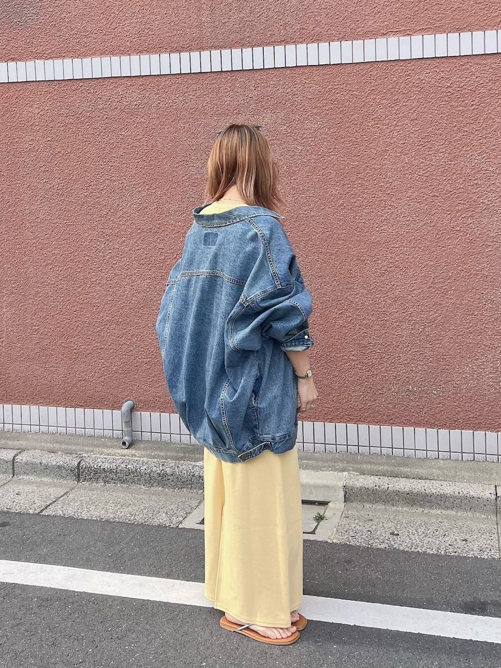 ブルー系のデニムジャケット、イエロー系のワンピースを着用したレディースの春コーディネートの2枚目の写真