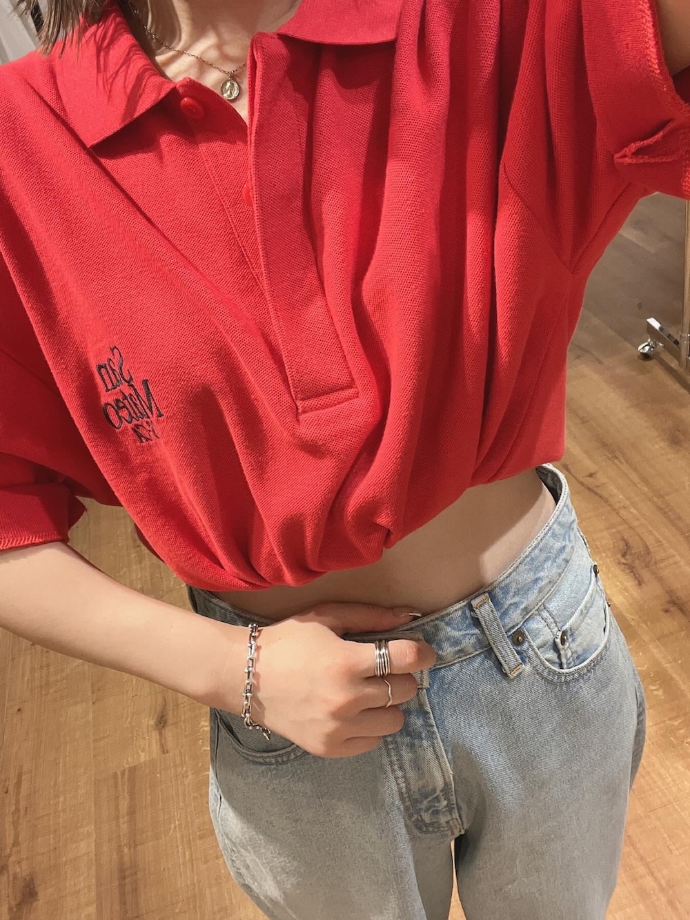 レッド系のポロシャツ、ブルー系のデニムパンツを着用したレディースの春コーディネートの2枚目の写真