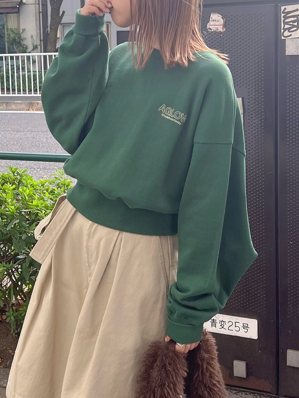 グリーン系のスウェット、ベージュ系のチノパンツ、ブラウン系のハンドバッグを着用したレディースの秋コーディネートの3枚目の写真