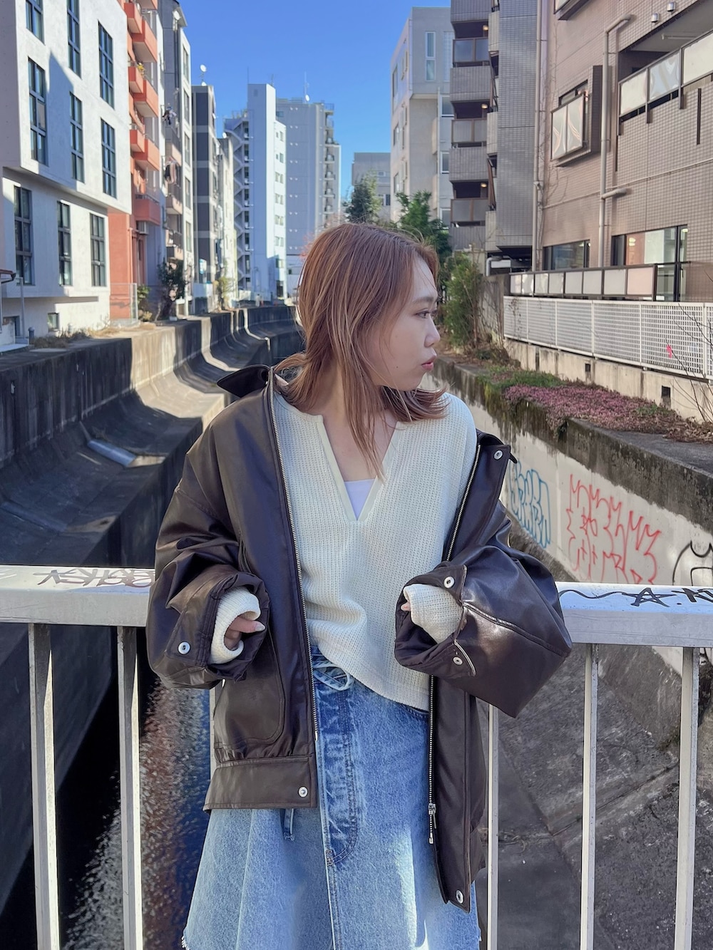 ブラウン系のブルゾン、イエロー系のTシャツ/カットソー、ブルー系のスカートを着用したレディースの冬コーディネートの2枚目の写真