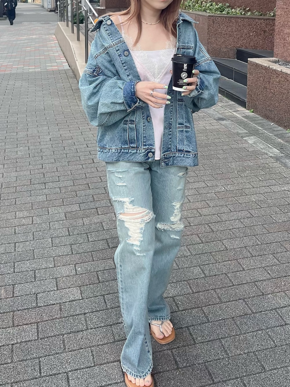 ブルー系のデニムジャケット、ピンク系のキャミソール、ブルー系のデニムパンツを着用したレディースの春コーディネートの2枚目の写真