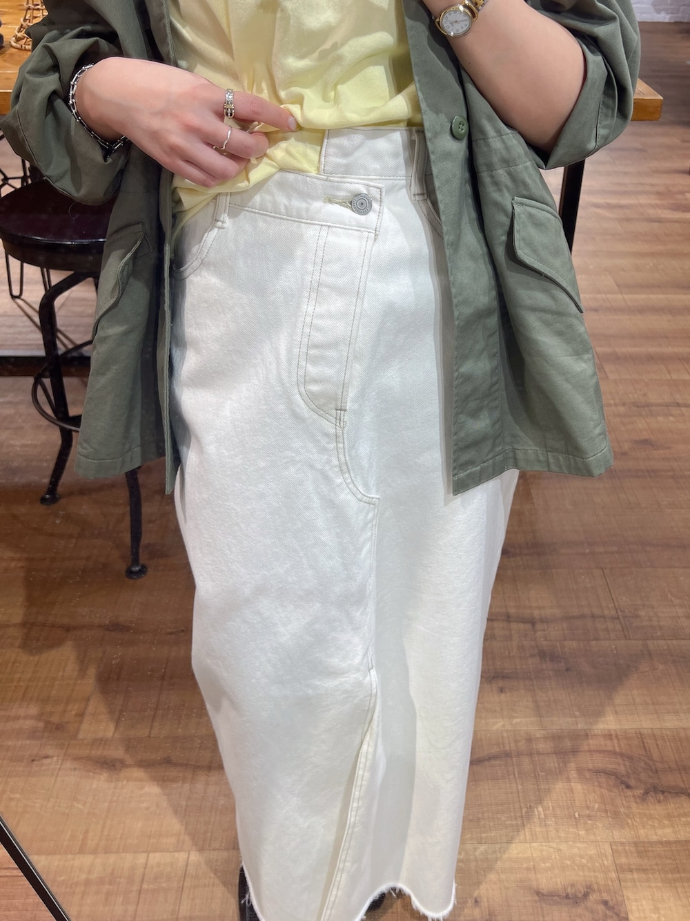 グリーン系のブルゾン、イエロー系のTシャツ/カットソー、ホワイト系のスカートを着用したレディースの春コーディネートの2枚目の写真