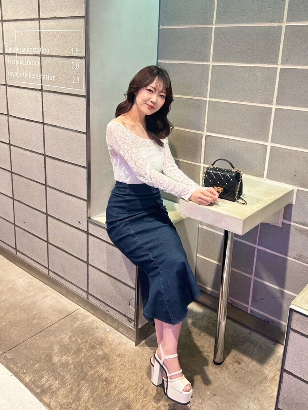 ブルー系のスカート、ブラック系のショルダーバッグ、ホワイト系のTシャツ/カットソーを着用したレディースの春コーディネートの4枚目の写真
