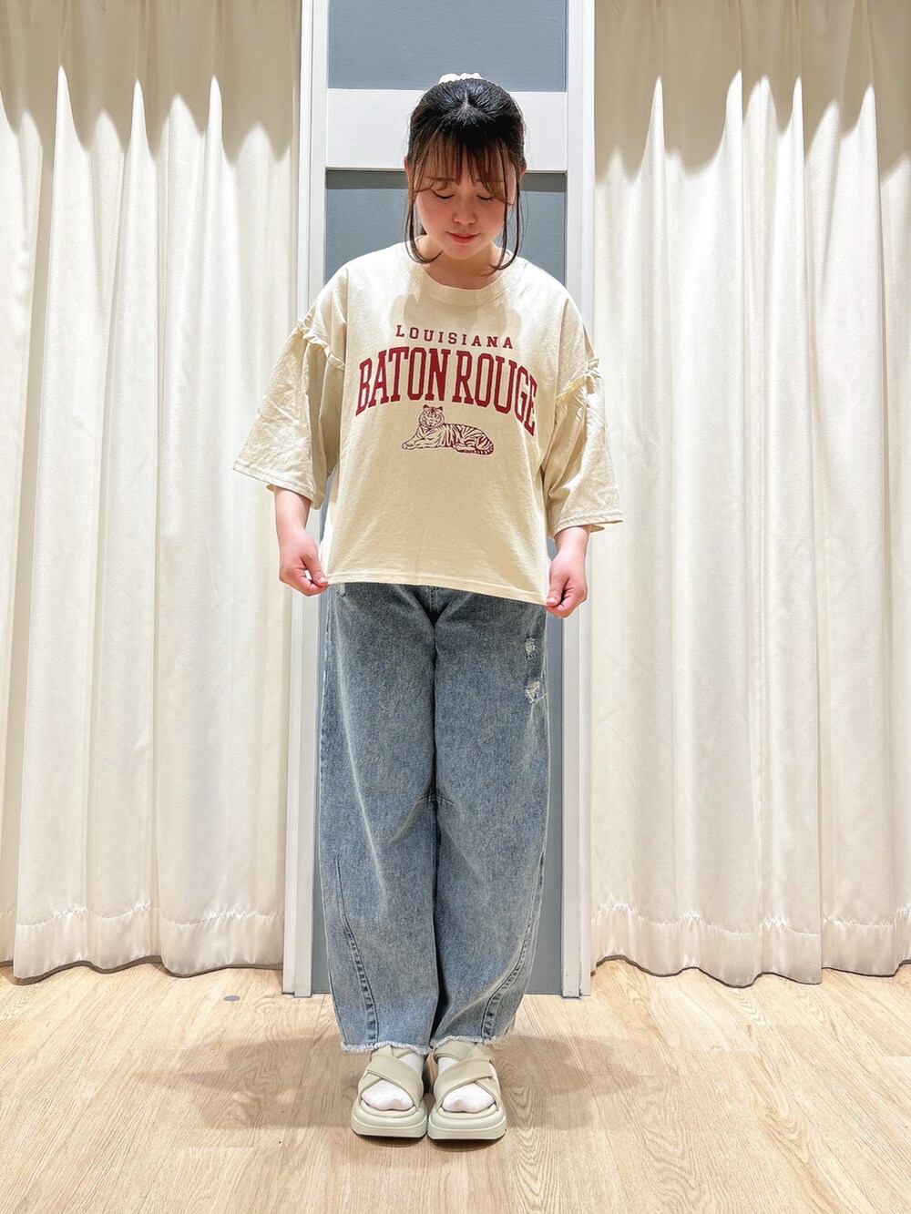 ブルー系のデニムパンツ、ホワイト系のハンドバッグ、ベージュ系のドレスシューズを着用したレディースの春コーディネートの2枚目の写真