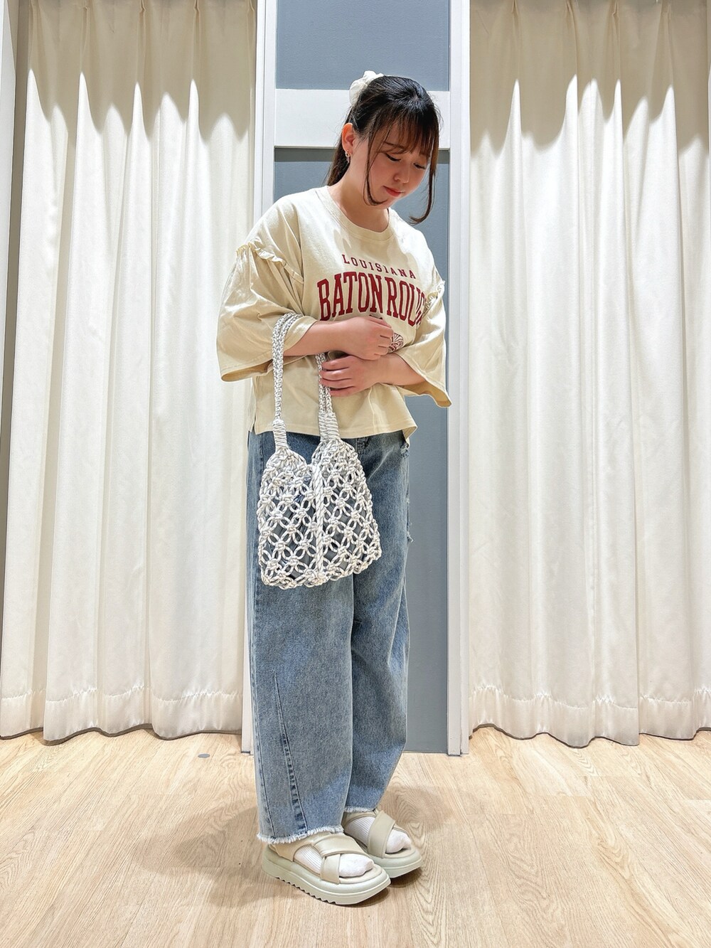 ブルー系のデニムパンツ、ホワイト系のハンドバッグ、ベージュ系のドレスシューズを着用したレディースの春コーディネートの3枚目の写真